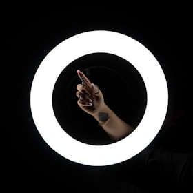 a person holding a cell phone in front of a circular light
