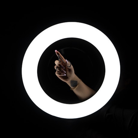 a person holding a cell phone in front of a circular light