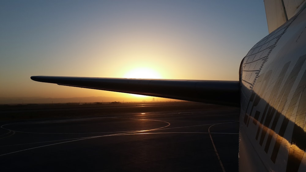 the sun is setting over the wing of an airplane