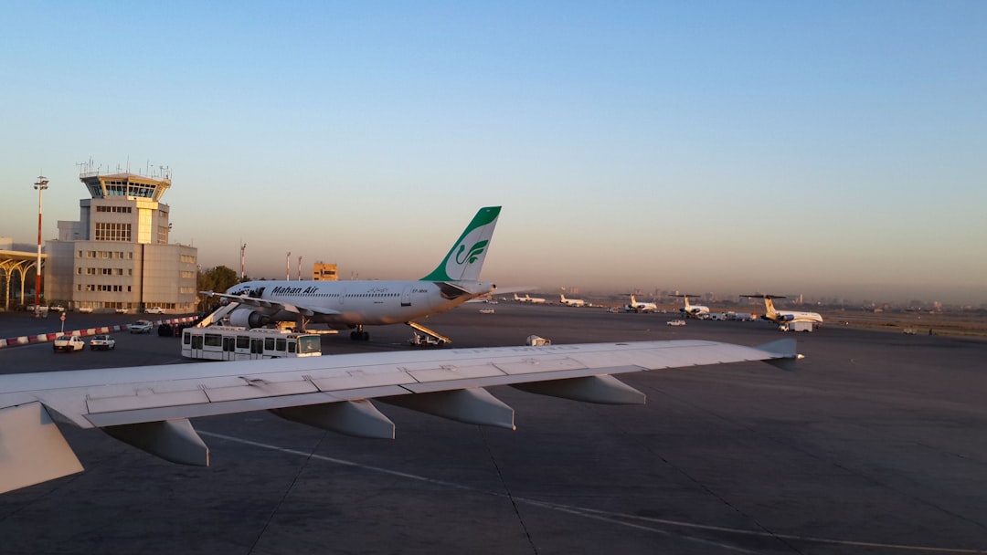 a large jetliner sitting on top of an airport tarmac, air traffic control tower of Mashhad International Airport and Mah
