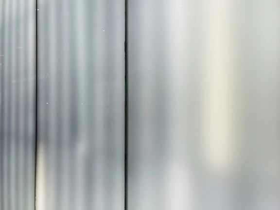 Close-up of a sleek glass office partition with silver framing reflecting soft light.
