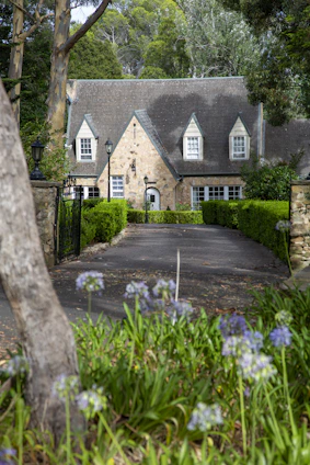 Cozy countryside home with a stone facade and blooming flower beds in front.