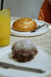 a plate with a donut on it next to a glass of orange juice