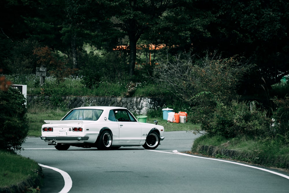 a white car driving down a curvy road