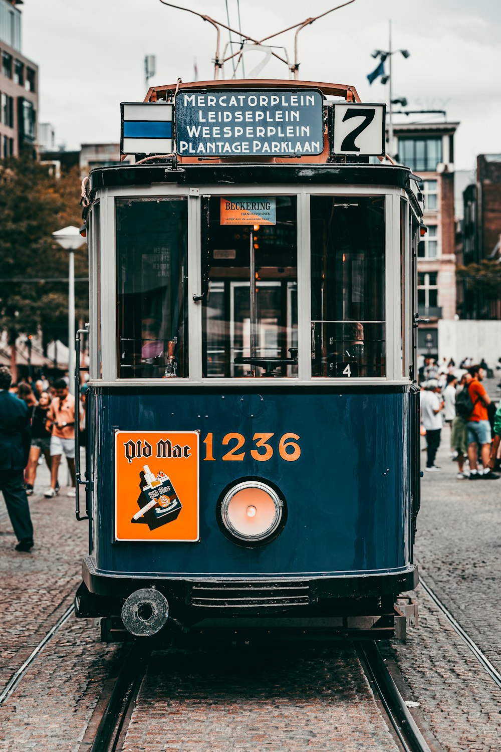 a blue trolley car on a city street