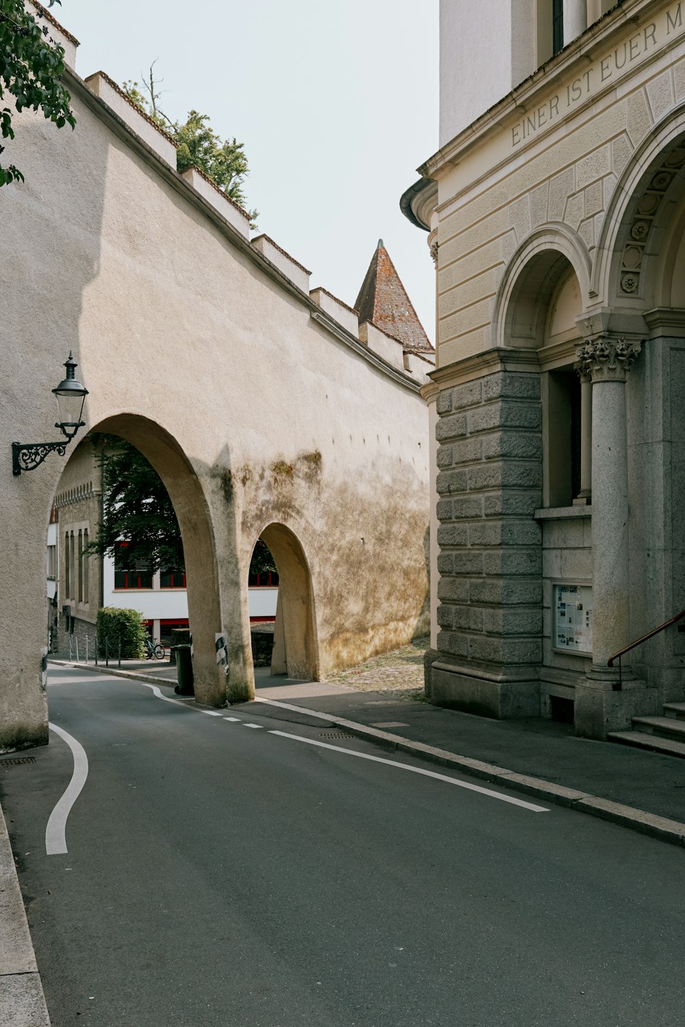 an empty street with arches and a clock tower in the background