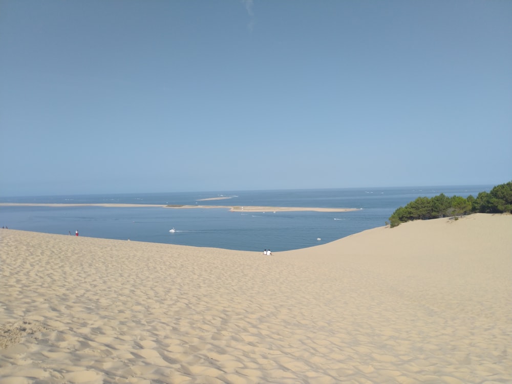 une plage de sable avec un plan d’eau au loin