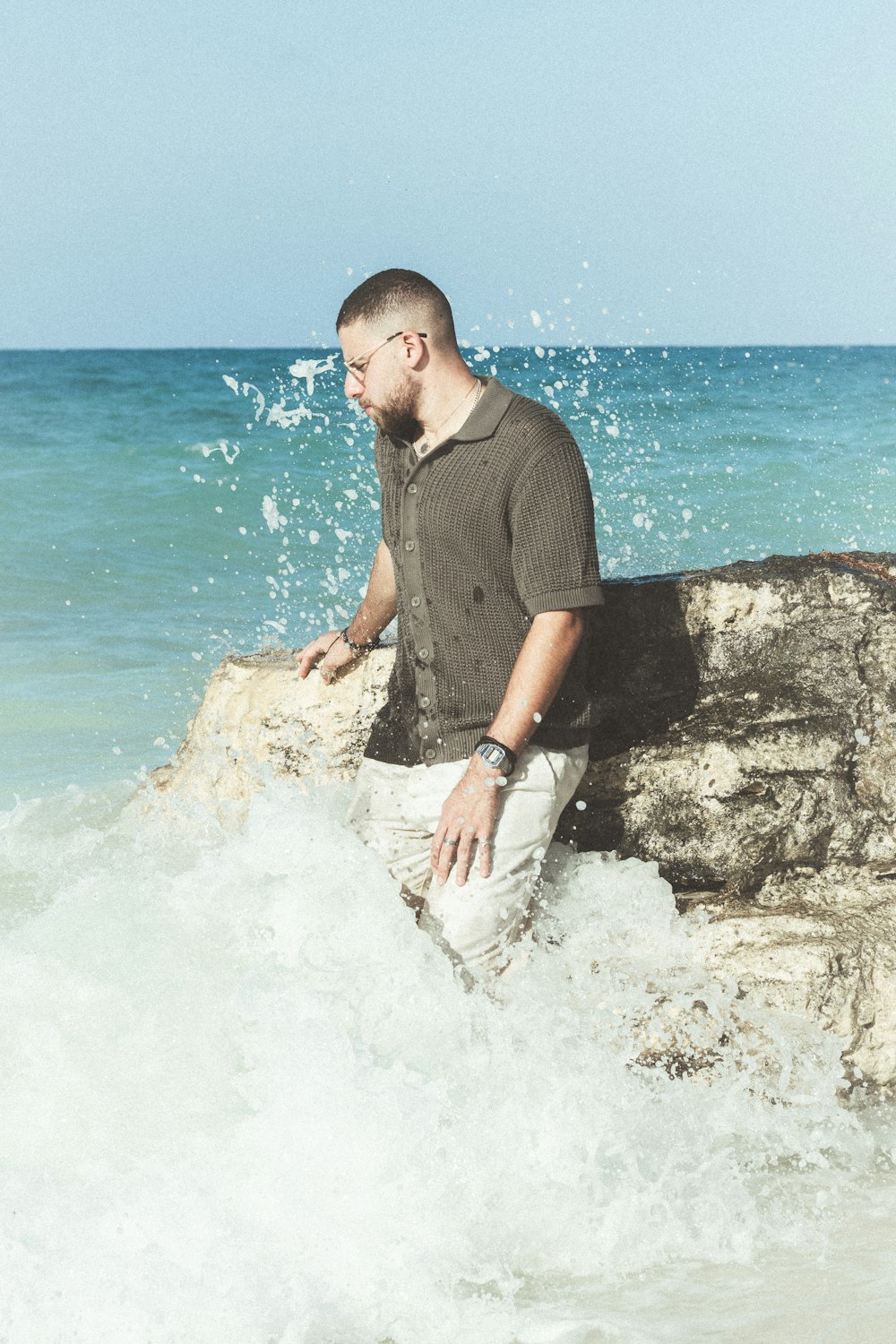 a man sitting on a rock in the ocean