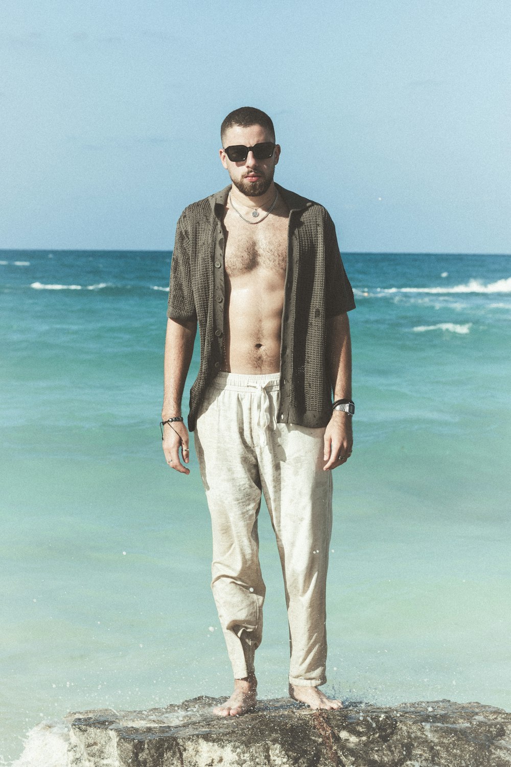 a man standing on top of a rock near the ocean