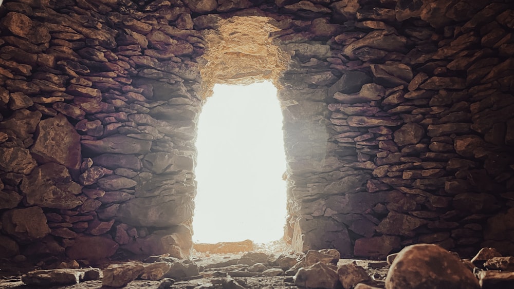 uma janela em uma parede de pedra com uma luz que vem através dela