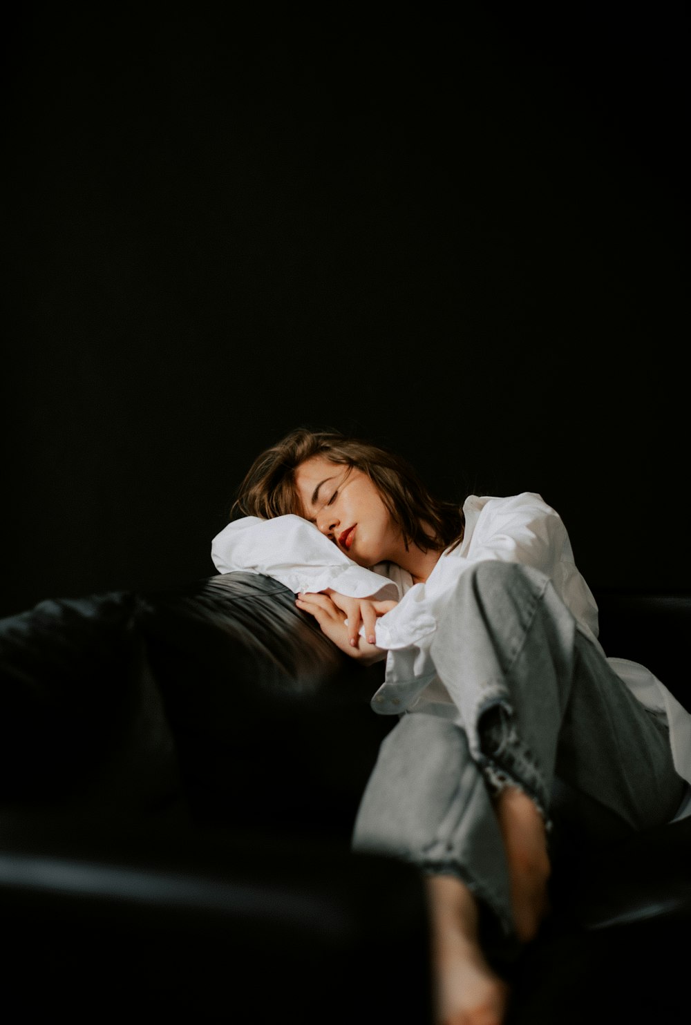 a woman laying on top of a black couch