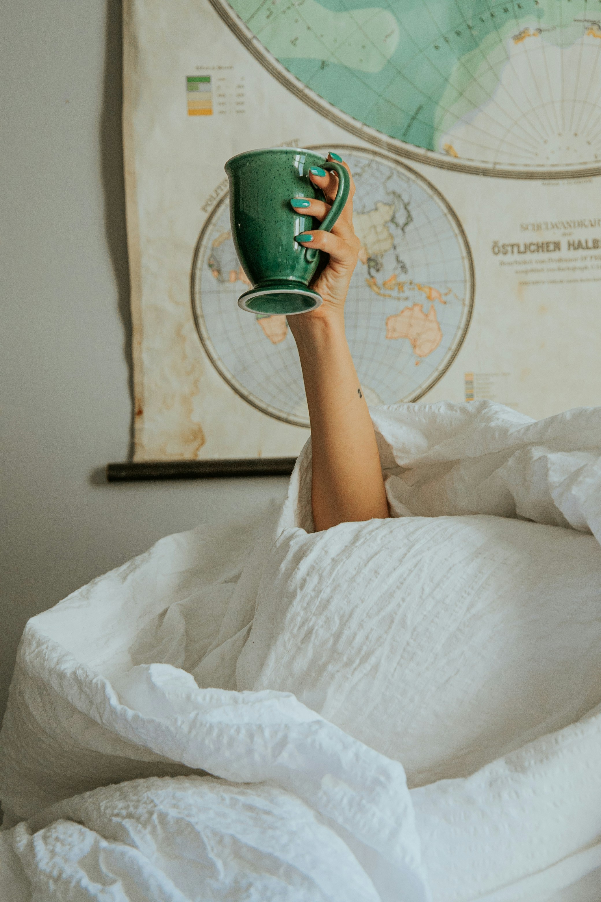 una persona sdraiata nel letto con una tazza in mano