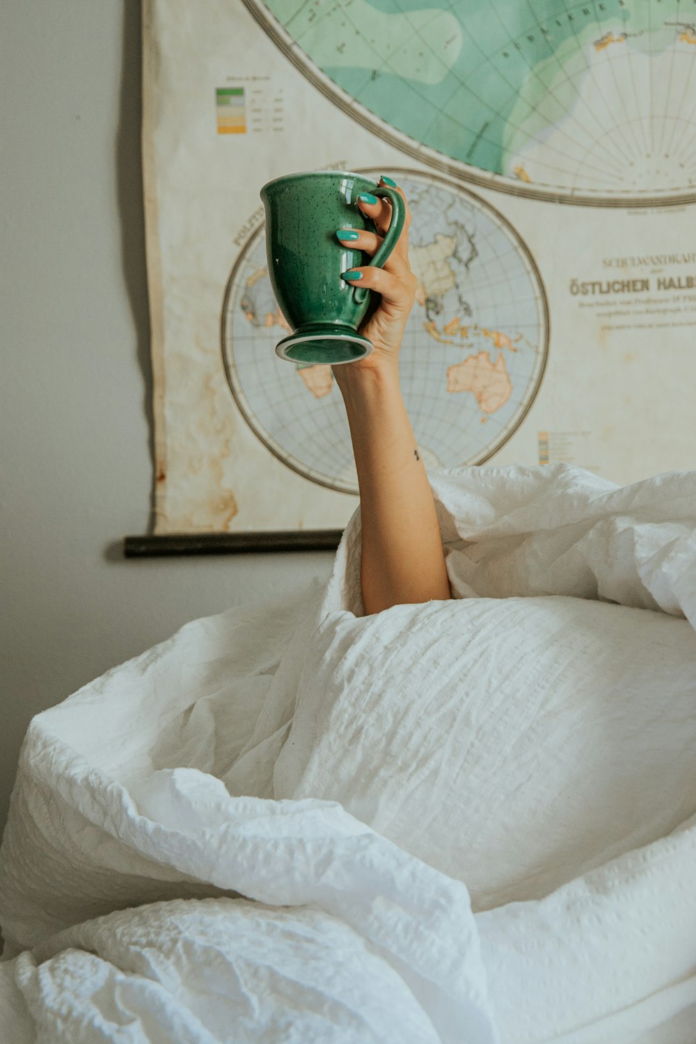a person laying in bed with a cup in their hand