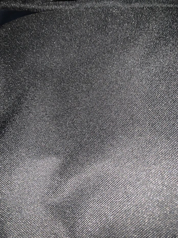 Close-up shot of a textured gray fabric with industrial metal details, reflecting the brand's aesthetic.