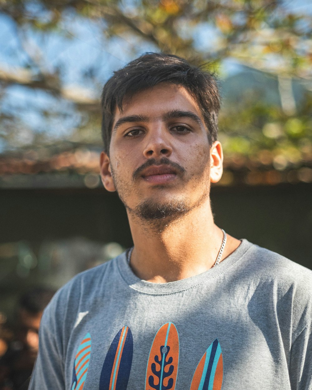 a man standing in front of a tree wearing a shirt with surfboards on it