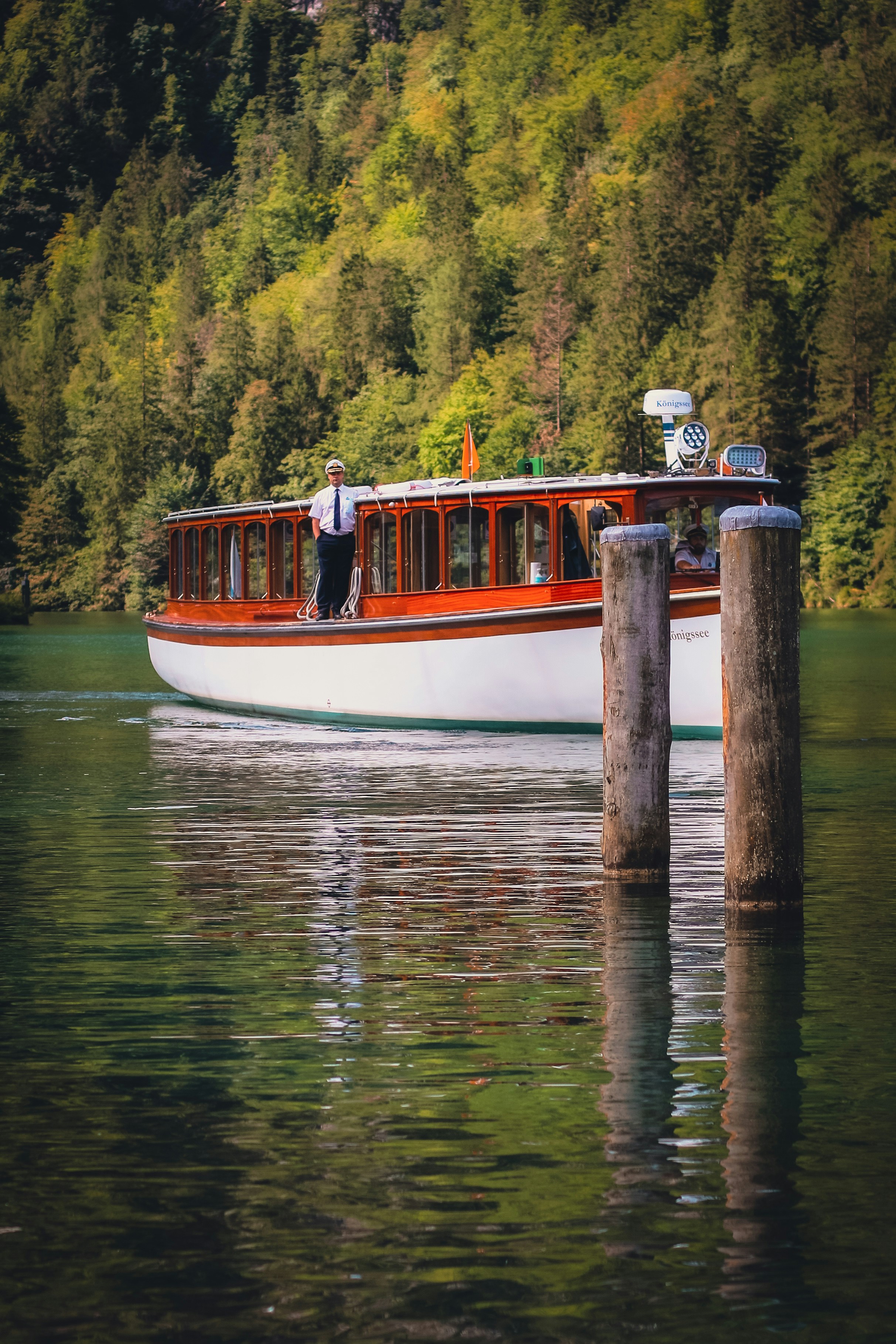 a red and white boat floating on top of a lake