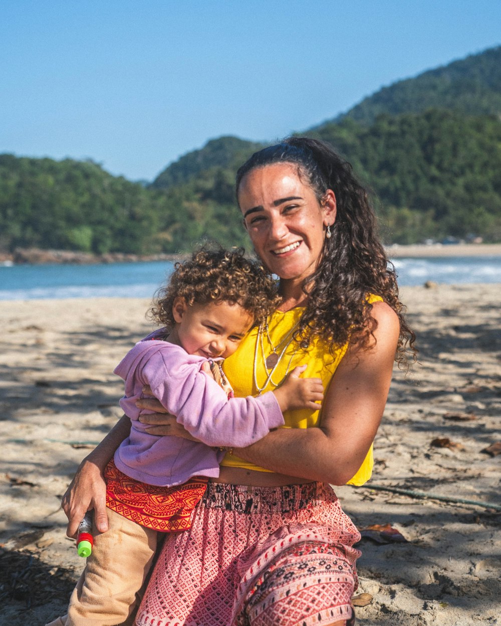 a woman holding a child on a beach