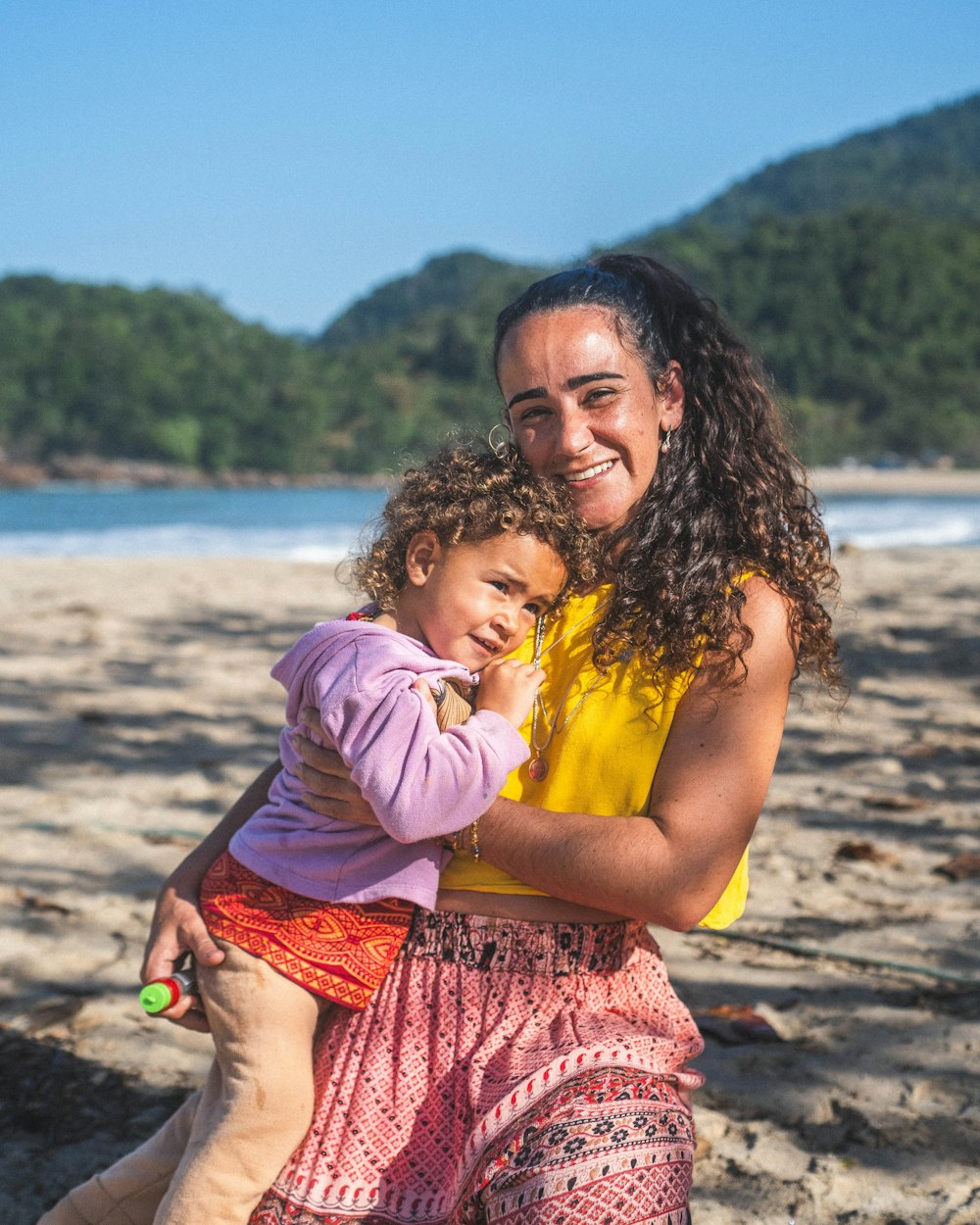 a woman holding a little girl on a beach