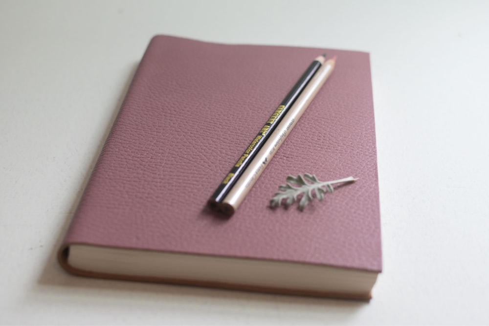 a pink notebook with a pen on top of it