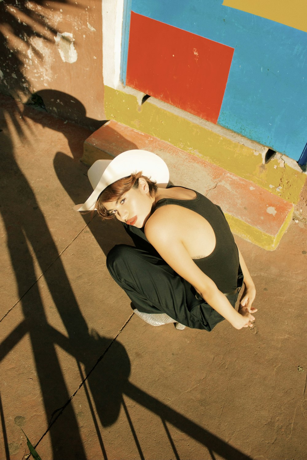 a woman sitting on the ground wearing a hat