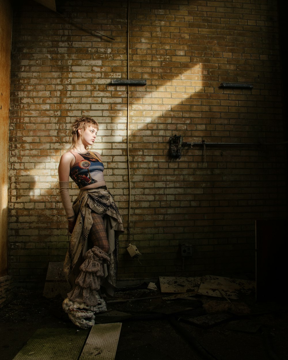 a woman in a dress standing in front of a brick wall