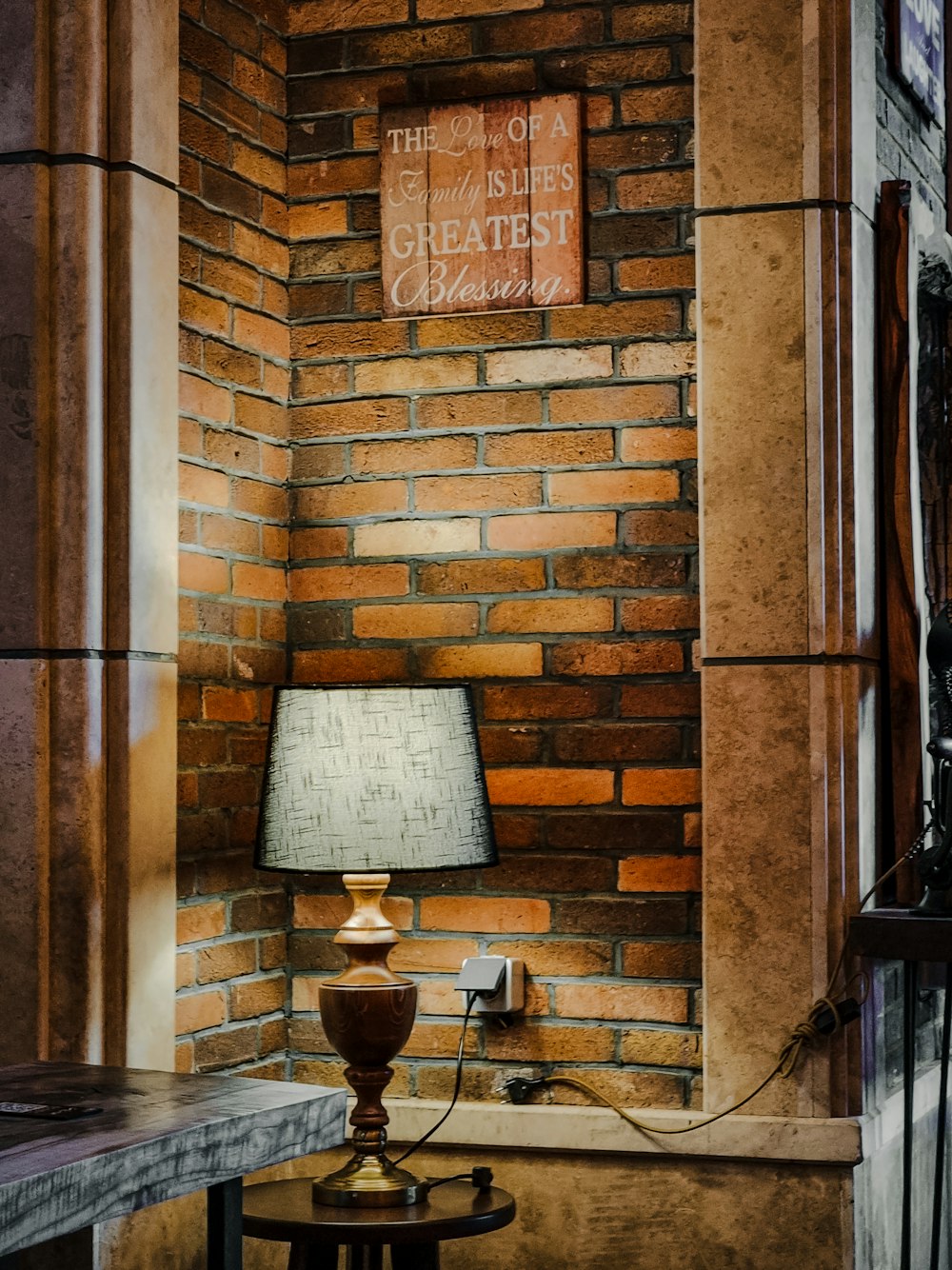 a lamp on a table next to a brick wall