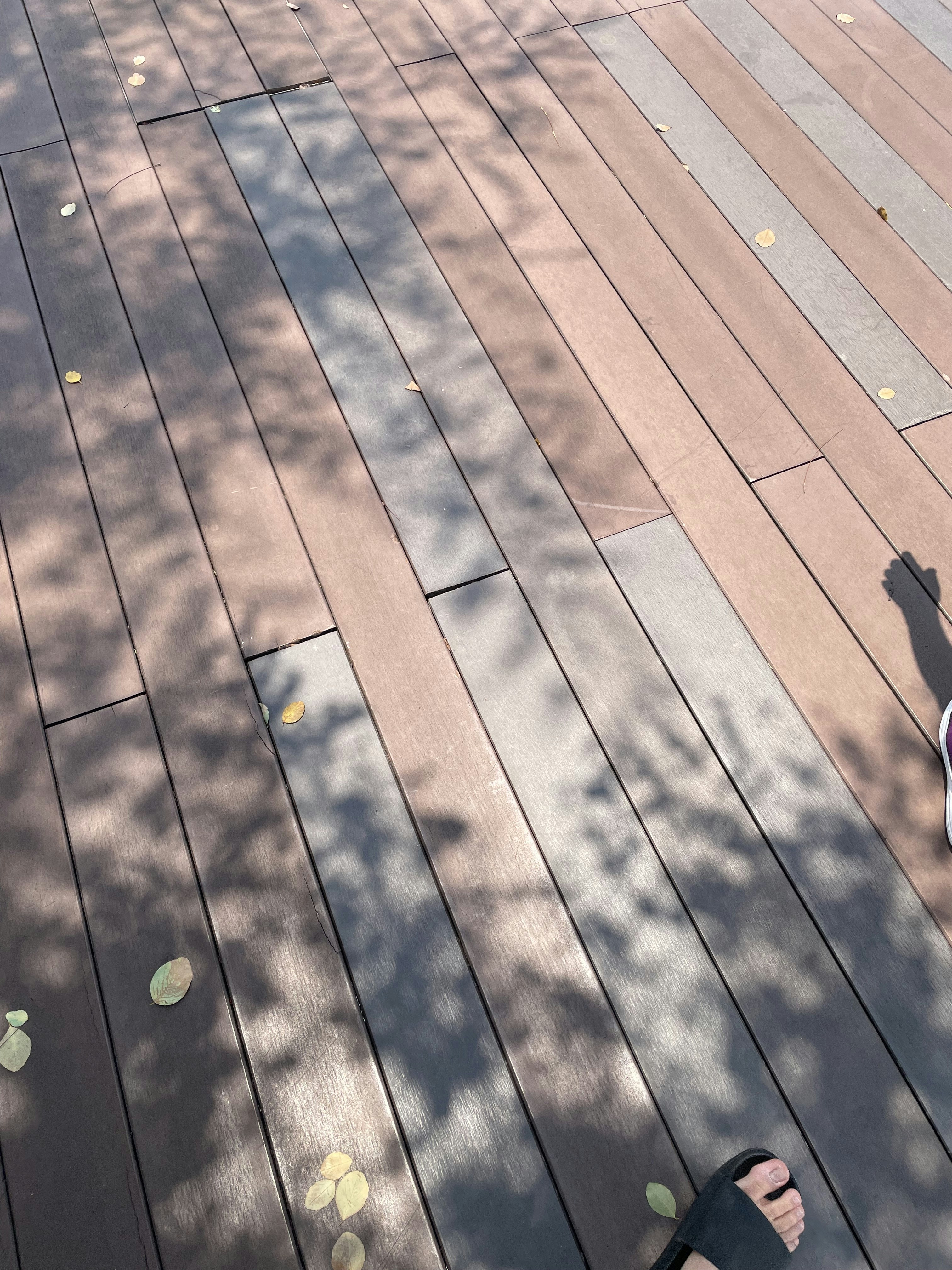 Deck design consultant comparing wood and composite board samples with homeowners on a deck frame