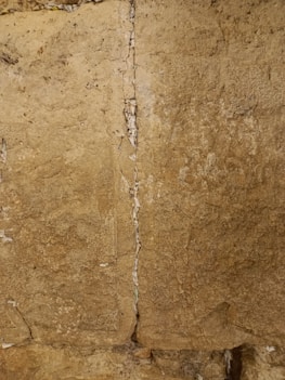 A clear photo showing a note folded and tucked securely inside the Western Wall stones.