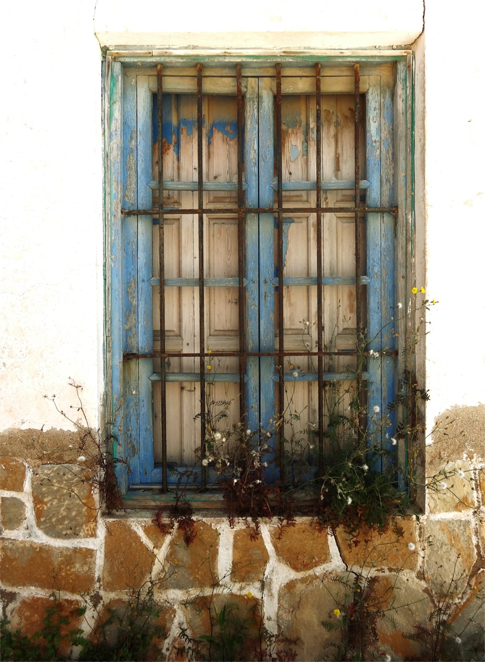 a window with a blue frame on a stone wall