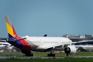 A sleek cargo airplane taking off from a bustling international airport runway.
