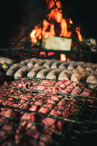 A vibrant, close-up shot of sizzling grilled meats and chorizos on a rustic barbecue grill.