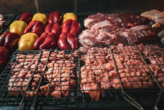 Close-up of a sizzling grill with a variety of meats and vegetables being cooked.
