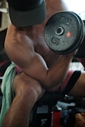 A strong personal trainer demonstrating correct dumbbell curl form.