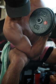 A strong personal trainer demonstrating correct dumbbell curl form.