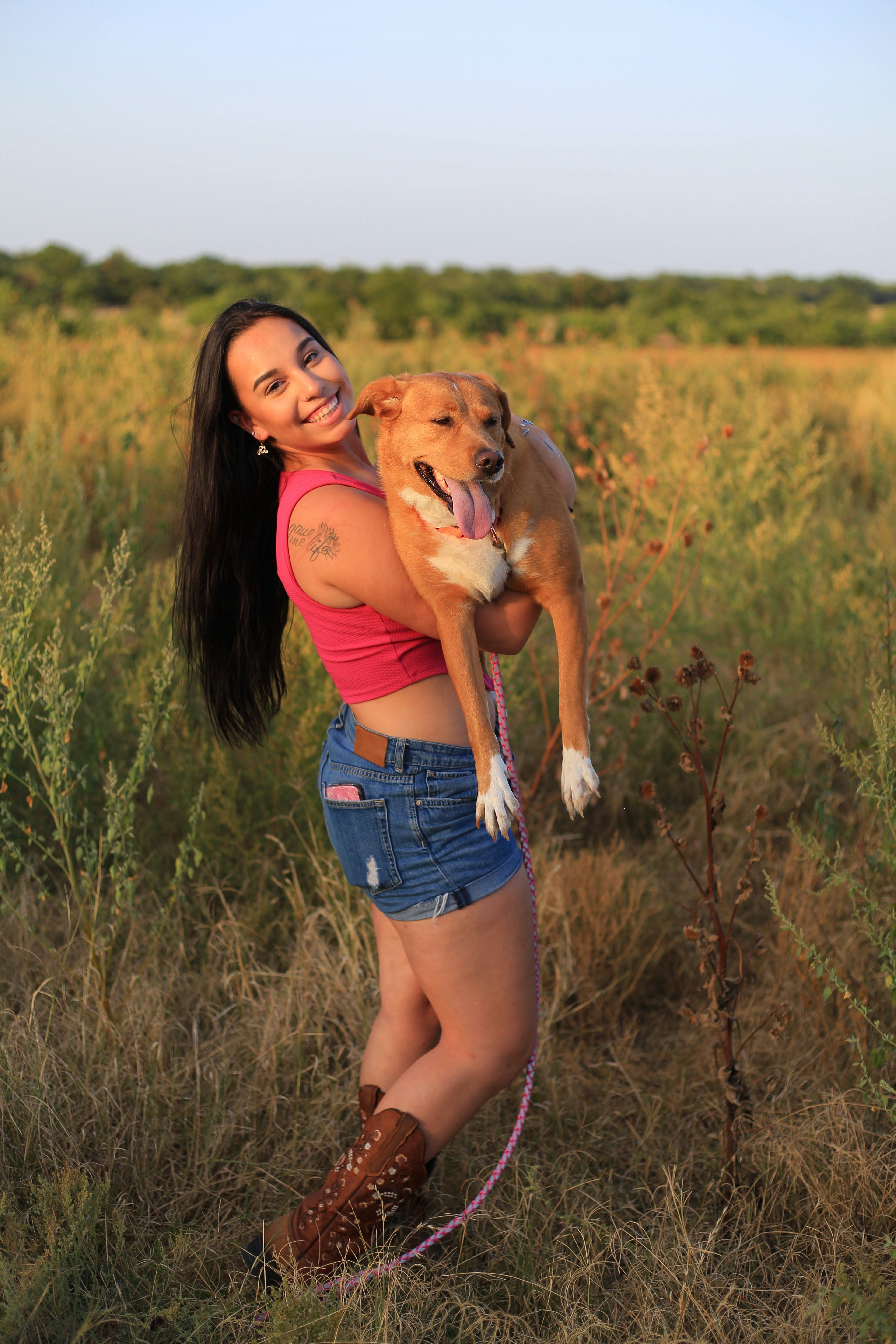a woman holding a dog in a field