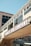 A commercial building facade with large windows and a prominent sign reading 'CANNERY ROW COMPANY'. The architecture features a beige exterior with glass panels and an overhanging structure. Underneath, there are additional storefront signs with various brand names like Coca-Cola.
