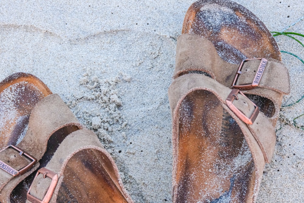 un paio di scarpe marroni seduti sulla cima di una spiaggia sabbiosa