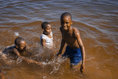 Children laughing as they splash in a sparkling swimming pool on a sunny day.