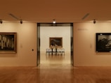 Elegant dark gallery wall showcasing a large, luminous painting with subtle golden highlights.