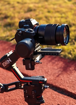 A high-end Sony camera mounted on a DJI Ronin gimbal, positioned outdoors on a track or pathway with grass in the background. The camera setup suggests professional-grade equipment used for capturing high-quality images or videos.