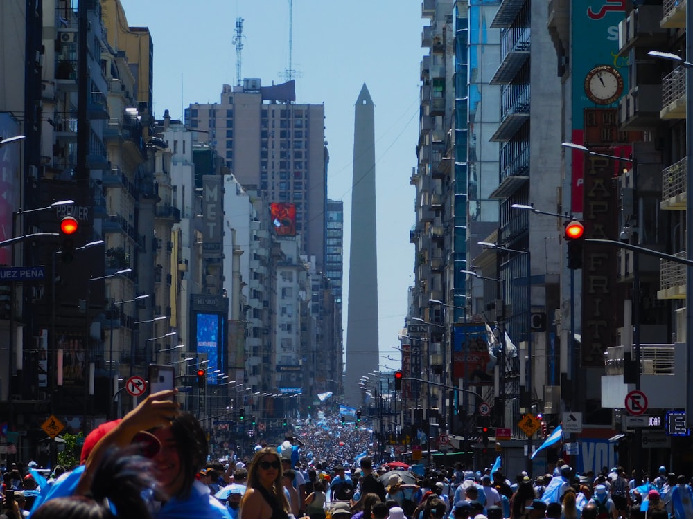 a crowd of people walking down a street next to tall buildings