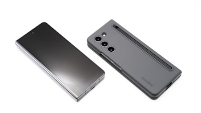Two modern smartphones are displayed on a white background. One phone lies flat with its screen facing upward, showcasing a sleek, reflective surface. The other phone, seen from the back, features a matte case with a camera module and a stylus inserted into a slot.