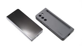Two modern smartphones are displayed on a white background. One phone lies flat with its screen facing upward, showcasing a sleek, reflective surface. The other phone, seen from the back, features a matte case with a camera module and a stylus inserted into a slot.