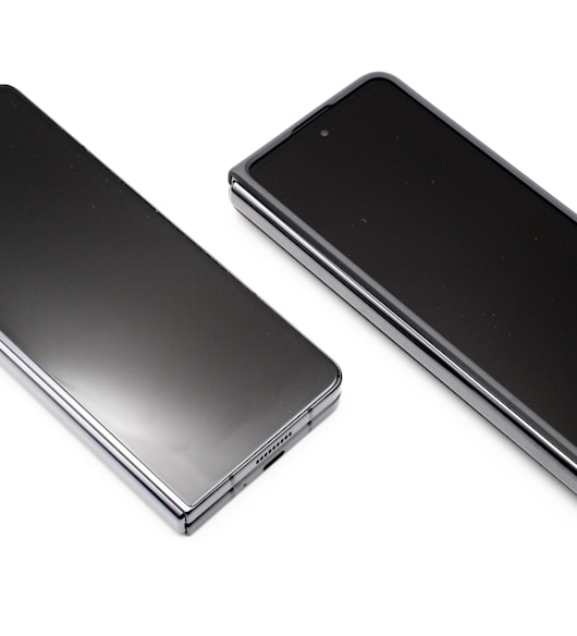 two black cell phones side by side on a white surface