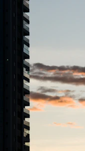 Sunset view of a high-rise building with illuminated balconies.
