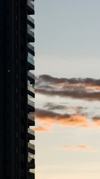 A high-rise apartment building with balconies overlooking a cityscape at sunset.