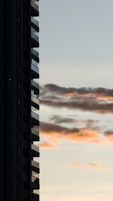 Modern condo building with balconies overlooking a cityscape at sunset.