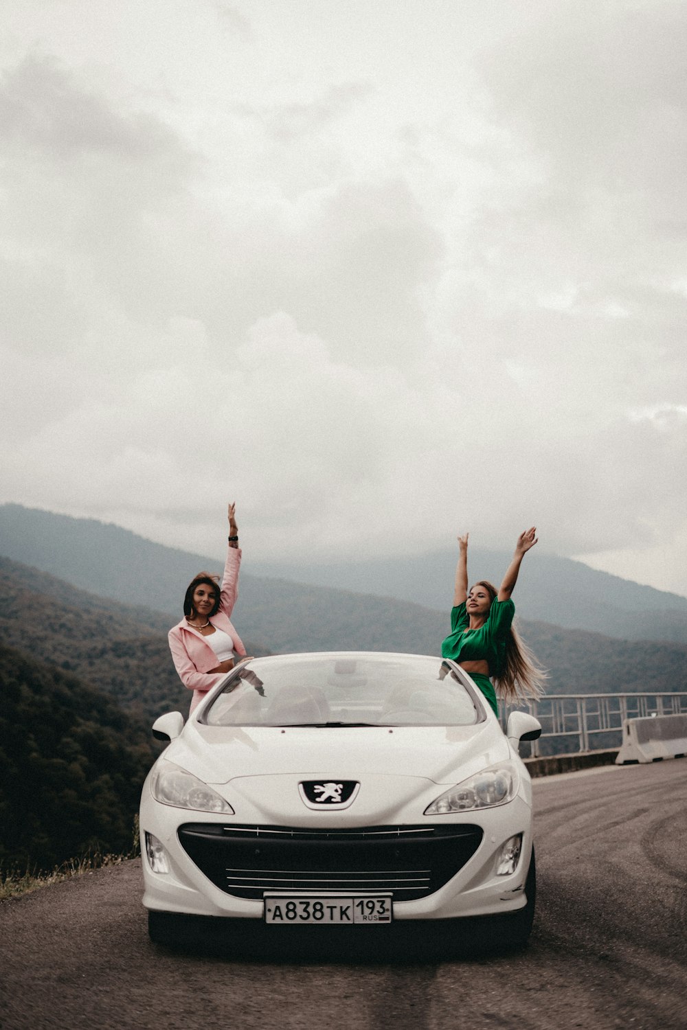 two women standing on the hood of a car