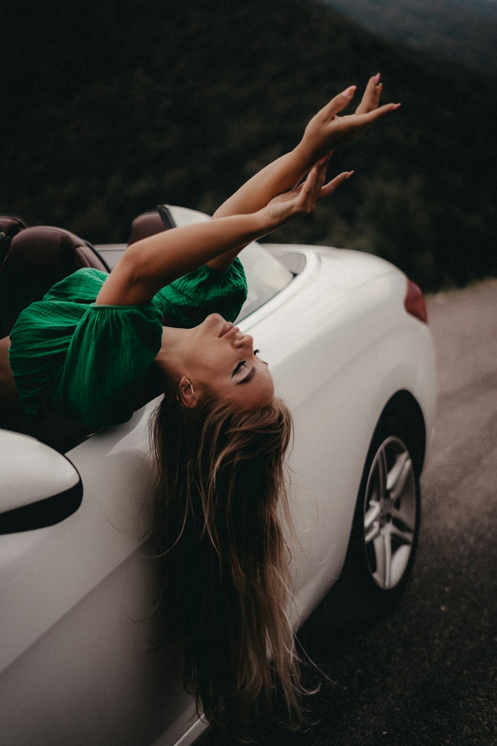 a woman laying on the back of a white car