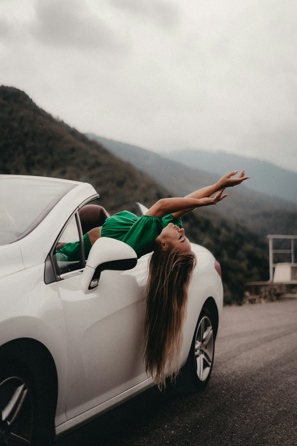 a woman leaning on the side of a white car